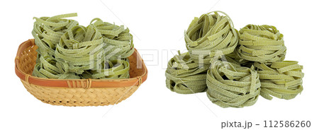 Raw tagliatelle green pasta with spinach in a wicker basket isolated on white background 112586260