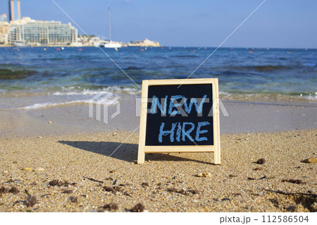 New Hire symbol. Concept words New Hire on black chalk background. Beautiful sea background. Business and New Hire concept. Copy space. 112586504