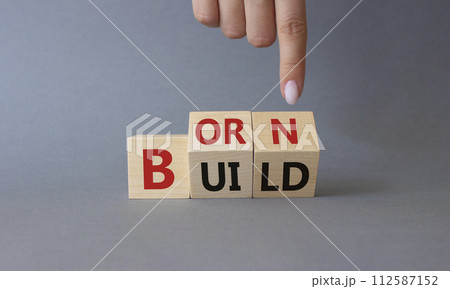 Born and Build symbol. Businessman hand points at turned wooden cubes with words Build to Born. Beautiful grey background. Business and Born and Build concept. Copy space. 112587152