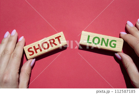Short vs Long symbol. Concept word Short vs Long on wooden blocks. Businessman hand. Beautiful red background. Business and Short vs Long concept. Copy space 112587185