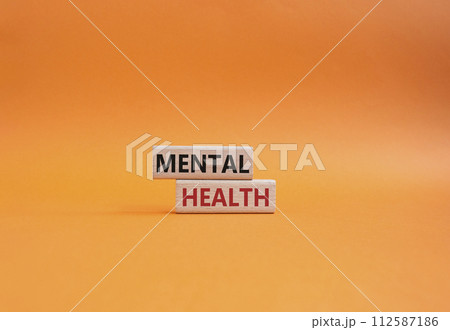 Mental Health symbol. Concept word Mental Health on wooden blocks. Beautiful orange background. Psychology and Mental Health concept. Copy space 112587186
