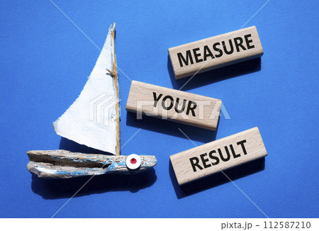 Measure your Result symbol. Concept words Measure your Result on wooden blocks. Beautiful blue background with boat. Business and Measure your Result concept. Copy space. 112587210
