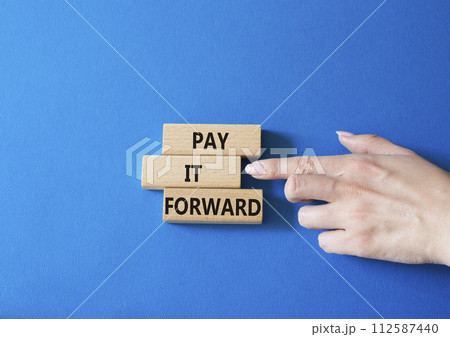 Pay it forward symbol. Concept words Pay it forward on wooden blocks. Beautiful blue background. Businessman hand. Business and Pay it forward concept. Copy space. 112587440