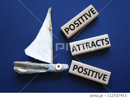 Positive attracts Positive symbol. Wooden blocks with words Positive attracts Positive. Beautiful deep blue background with boat. Business and Positive attracts Positive concept. Copy space. 112587453