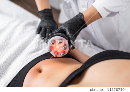 A cosmetologist expertly utilizes RF technology to conduct skin tightening and body contouring procedures to refine the abdominal area of a young woman A cosmetologist expertly utilizes RF technology to conduct skin tightening and body contouring procedures to refine the abdominal area of a young woman 112587504