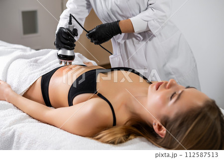 Young woman is lying while getting RF lifting of the body in a spa beauty salon 112587513