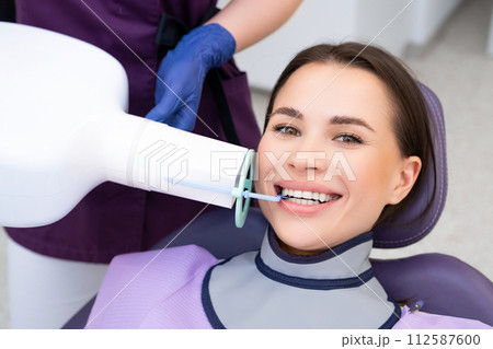 A female patient smiles as she receives a teeth X ray at the dental clinic A female patient smiles as she receives a teeth X ray at the dental clinic 112587600
