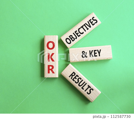 OKR objectives and key results symbol. Wooden blocks with words OKR objectives and key results. Beautiful green background. Business and OKR concept. Copy space. 112587730
