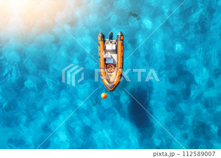 Aerial view of beautiful orange boat in blue sea at sunset 112589007