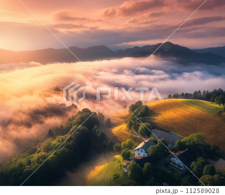 Aerial view of meadows and mountains in low clouds at sunrise 112589028