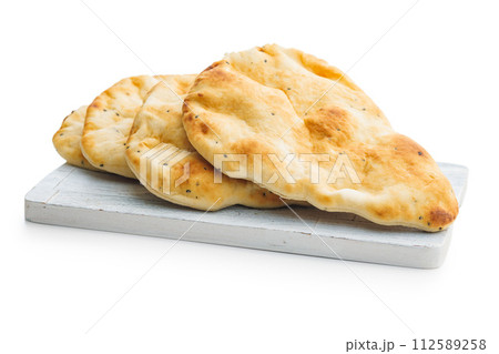 Freshly Baked Naan Bread on cutting board isolated on white background. Freshly Baked Naan Bread on cutting board isolated on white background. 112589258