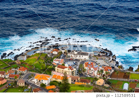 View of the village of Porto Moniz with volcanic lava pool, Atlantic ocean and green forest. Madeira Island, Portugal 112589531