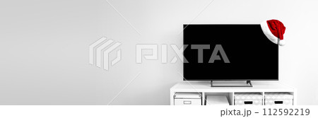 Santa Claus hat on Lcd tv on white shef at modern room interior Santa Claus hat on Lcd tv on white shef at modern room interior 112592219