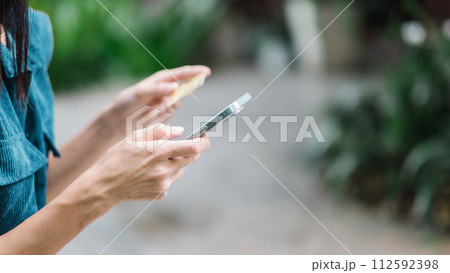 Close up view of a woman hands holding a credit card and a smartphone, likely engaging in an online transaction. 112592398