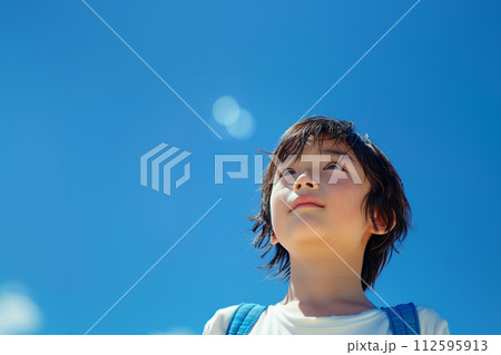 青空を見上げる小学生の男の子 112595913