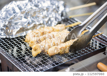 バーベキューコンロで焼き鳥を焼くイメージ バーベキューコンロで焼き鳥を焼くイメージ 112597060