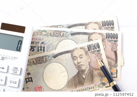 福沢諭吉の肖像の一万円紙幣と電卓、ペン 112597452