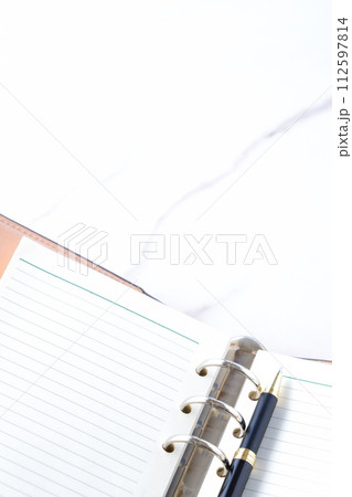 リング式のシステム手帳でデスクワークをしているイメージ 112597814