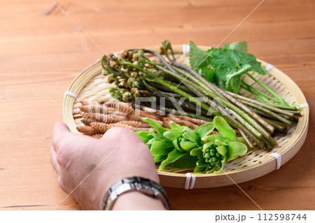 ザルに盛った春の食材 （ ふきのとう 蕨 三つ葉 つくし ) 112598744