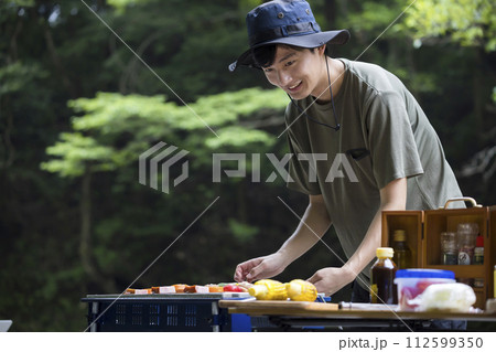 バーベキューイメージ　串焼きを焼く若い男性 112599350