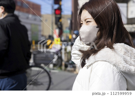 踏切待ちをするマスク姿の若い女性 112599959
