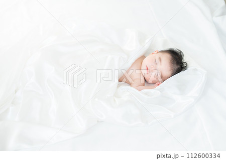 シーツに包まれて眠る生後4ヶ月の男の子 112600334
