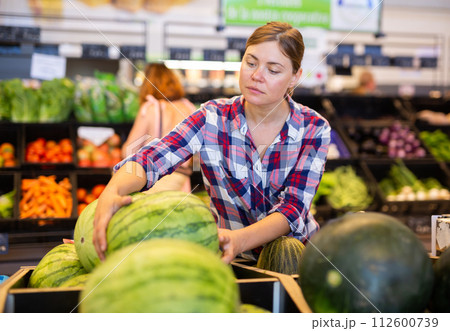 Woman choosing watermelon in supermarket Woman choosing watermelon in supermarket 112600739