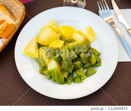 Plate contains light side dish of stewed vegetables - potatoes, green string beans, onions Plate contains light side dish of stewed vegetables - potatoes, green string beans, onions 112600935