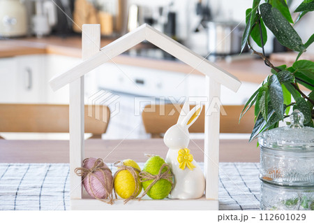 Key and tiny house of cozy home with Easter decor with rabbit and eggs on table of kitchen. Building, design, project, moving to new house, mortgage, insurance, rent and purchase real estate Key and tiny house of cozy home with Easter decor with rabbit and eggs on table of kitchen. Building, design, project, moving to new house, mortgage, insurance, rent and purchase real estate 112601029