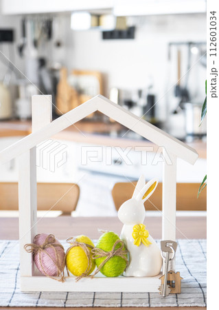 Key and tiny house of cozy home with Easter decor with rabbit and eggs on table of kitchen. Building, design, project, moving to new house, mortgage, insurance, rent and purchase real estate Key and tiny house of cozy home with Easter decor with rabbit and eggs on table of kitchen. Building, design, project, moving to new house, mortgage, insurance, rent and purchase real estate 112601034