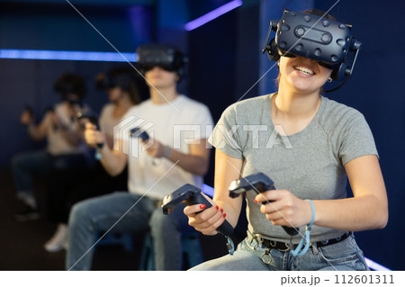 Excited young woman in VR goggles having fun in virtual reality room 112601311