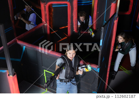 Two girls and two guys playing lasertag in labyrinth of lasertag arena Two girls and two guys playing lasertag in labyrinth of lasertag arena 112602187