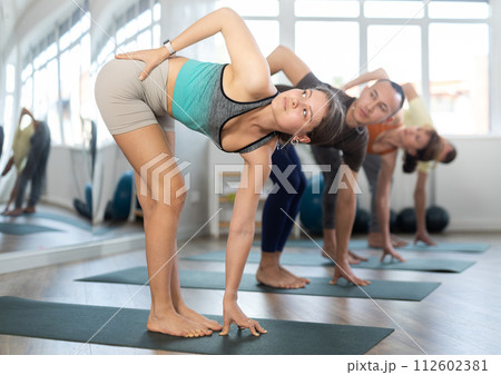 Attractive girl in sportswear using mat spend free time doing yoga for health and wellness together with group of people 112602381