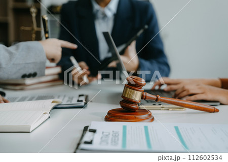 Justice and law concept. Team judge in a courtroom the gavel, working with digital tablet computer on table in sun light. 112602534