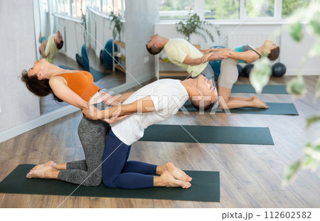 Two young people yogi doing balance back stretch acro yoga pose at sport gym. Healthy lifestyle modern activity Two young people yogi doing balance back stretch acro yoga pose at sport gym. Healthy lifestyle modern activity 112602582