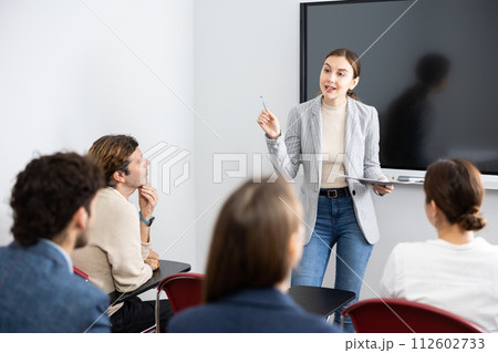 Young female professor explaining subject to classroom full of students 112602733
