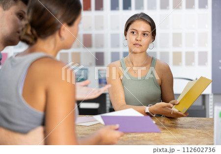 Seller of hardware store advises couple of buyer what ceramic tiles to buy 112602736