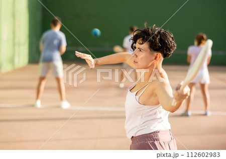 Portrait of sporty girl playing paleta fronton on outdoor court, ready to hit ball. Healthy and active lifestyle concept Portrait of sporty girl playing paleta fronton on outdoor court, ready to hit ball. Healthy and active lifestyle concept 112602983