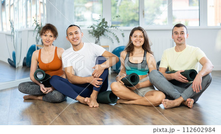 Happy portrait of four young people posing with mats, going to practicing yoga at gym Happy portrait of four young people posing with mats, going to practicing yoga at gym 112602984