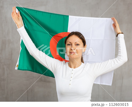 Adult cheerful woman holding Algeria flag Adult cheerful woman holding Algeria flag 112603015