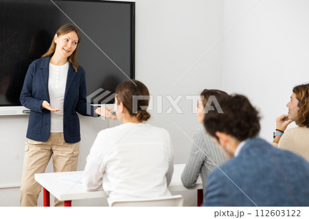 Experienced female teacher giving lecture to group of student 112603122