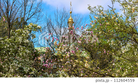 Spring Easter mood. Church with golden domes, blooming magnolia garden 112604559