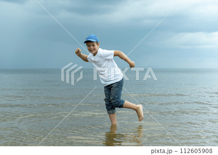 happy boy is standing in the water in the sea and fooling around happy boy is standing in the water in the sea and fooling around 112605908
