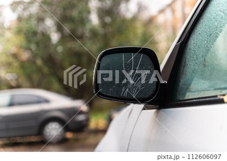 Close-up of a damaged exterior rearview mirror on a car. The image depicts a vehicle maintenance problem concept, highlighting the need for repair and maintenance. 112606097