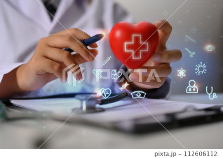 Closeup cardiologist holding red heart shape with virtual medical icons. Health care concept Closeup cardiologist holding red heart shape with virtual medical icons. Health care concept 112606112