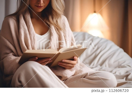 Woman Sitting on Bed Reading Book 112606720