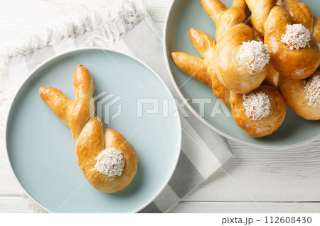 Funny sweet bunnies buns with coconut closeup on a white wooden background. Horizontal top view Funny sweet bunnies buns with coconut closeup on a white wooden background. Horizontal top view 112608430