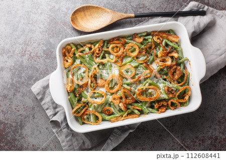 Homemade Green Bean Casserole with crispy fried onions on the baking dish. Horizontal top view Homemade Green Bean Casserole with crispy fried onions on the baking dish. Horizontal top view 112608441