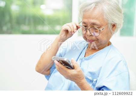 Asian senior woman wearing eyeglasses or vision glasses using a smartphone at home care service. Asian senior woman wearing eyeglasses or vision glasses using a smartphone at home care service. 112609922