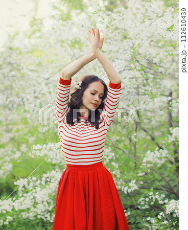 Lovely happy smiling young woman in spring blooming garden with white flowers on the trees in park Lovely happy smiling young woman in spring blooming garden with white flowers on the trees in park 112610439